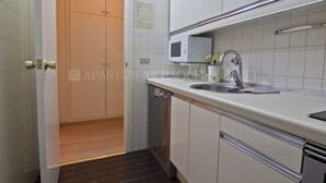 Una cocina con gabinetes blancos, microondas, fregadero y lavavajillas.
