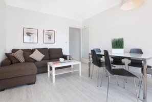 Un salon moderne comprenant un canapé, une table basse et un coin repas avec des chaises et une table.