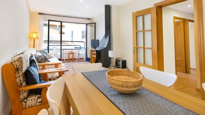 Una sala de estar moderna con un sofá, una mesa de comedor y sillas. Hay un ventanal con vistas al exterior.