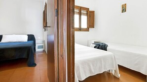 A room with two beds, one with a dark blue bedspread and the other with a white one. There is a wooden door frame and a small picture on the wall. - 1BON 2 - Basic apartment for 6 persons in Llafranc, in front of the sea (Llafranc)