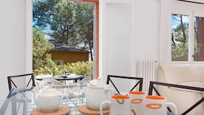 A glass table with white teapots and orange mugs, a white chair, and a view of a yellow building and trees. - 1CAR PL - Basic apartment with communal pool near Llafranc beach (Llafranc)