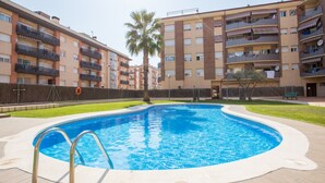 Una piscina rodeada de edificios de apartamentos con balcones y una palmera.