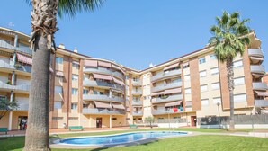 Un hotel de varios pisos con balcones, piscina y una palmera.