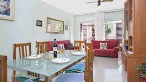 Un comedor con una mesa de vidrio, sillas, un sofá rojo y un armario de madera.