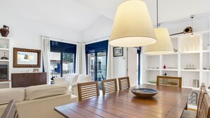 Un espace repas comprenant une table en bois, des chaises et un grand luminaire suspendu.