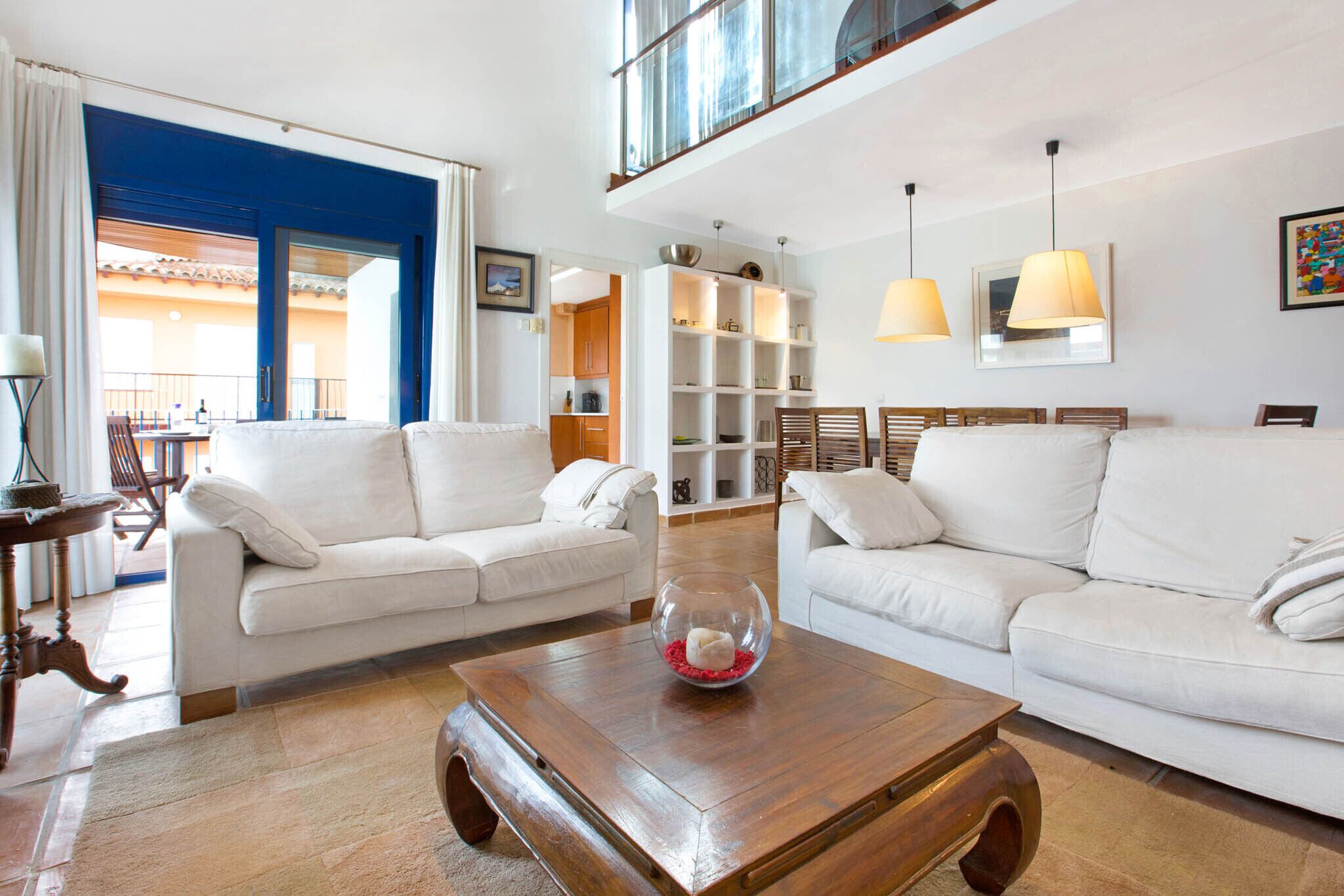 A spacious living room with two white sofas, a wooden coffee table, and a glass bowl.