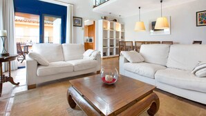 Un salon spacieux avec deux canapés blancs, une table basse en bois et un saladier en verre.