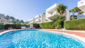 A swimming pool with clear blue water, surrounded by modern buildings and greenery. - 1OP 01 - Apartment located in Pals, in a residential complex with swimming pool, 400 m from the beach (Pals)