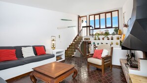A living room with a sofa, armchair, coffee table, and a staircase leading to a balcony with plants. - 1ROS 01 - 150 m2 house with communal pool and parking, very close to Llafranc beach (Llafranc)