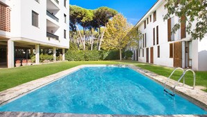 A rectangular swimming pool with a metal ladder, surrounded by a well-maintained lawn and white buildings with balconies. - 1ROS 01 - 150 m2 house with communal pool and parking, very close to Llafranc beach (Llafranc)