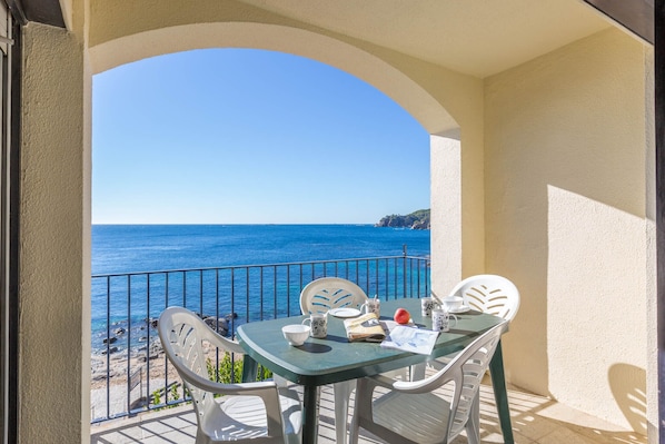 Ein Balkon mit Tisch und Stühlen mit Blick auf das Meer.