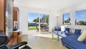 Una sala de estar moderna con un sofá azul, una mesa de centro de vidrio y un televisor sobre un mueble de madera.