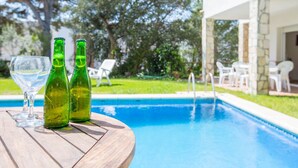 A wooden table with two green bottles and a glass near a swimming pool. - 1DIAZ 01 - Lovely and cozy villa with private pool and garden situated in a quiet residential area only 1km from the beautiful Aigua Xelida beach (Tamariu)