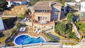 Une maison à deux étages dotée d’une piscine, d’un espace salon extérieur et d’une terrasse en pierre.