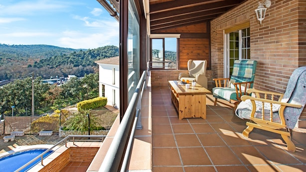 Un balcon avec une piscine, des meubles en bois et une vue sur la campagne.