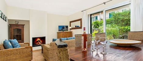 Una sala de estar acogedora con muebles de mimbre, una chimenea y una mesa de comedor con vasos.