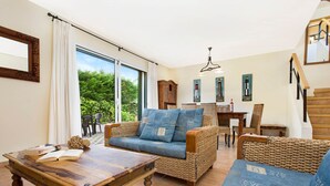 Un salon chaleureux avec un canapé, une table basse en bois et un coin repas comprenant des chaises et une table.