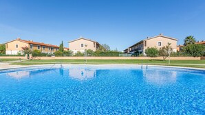 Une piscine entourée de bâtiments, avec un ciel bleu dégagé.