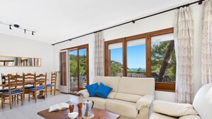 A living room with a sofa, a coffee table, and a dining area with chairs and a table. - 1CAR 01 - Basic apartment with communal pool near the beach of Llafranc (Llafranc)