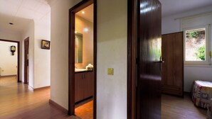 A hallway with wooden flooring, a wooden door, and a window with a view of greenery. - 2SEN01 - House with private pool located in a quiet area just 2.5 km from the beautiful beach of Canyelles (Lloret de Mar)