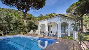 A poolside area with a clear blue pool, white lounge chairs, and a small building with arches. - 2SEN01 - House with private pool located in a quiet area just 2.5 km from the beautiful beach of Canyelles (Lloret de Mar)