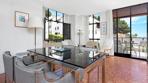 A modern dining area with a glass table, grey upholstered chairs, and a view of the outdoors. - 1PINEDA 01 - Cozy apartment for 8 persons  situated a few minutes walk from the beach of  Calella de Palafrugell (Calella de Palafrugell)