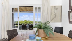 A dining table with two wine glasses, a potted fern, and a map on the wall.