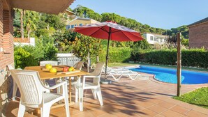 Une terrasse avec une piscine, du mobilier d’extérieur et une table garnie de fruits.