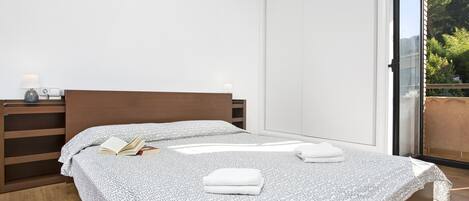 Ein modernes Schlafzimmer mit einem Holzkopfende, einer gemusterten Bettdecke und einem Nachttisch mit einer Lampe.