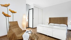 A modern bedroom with a large bed, a wicker chair, a floor lamp, and a wardrobe. - 2PON01 - Beautiful house with private pool located in a quiet area near the beach (Lloret de Mar)