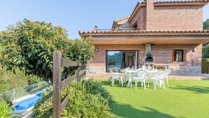 A house with a brick exterior, a stone foundation, a patio with outdoor furniture, and a swimming pool. - 2PON01 - Beautiful house with private pool located in a quiet area near the beach (Lloret de Mar)