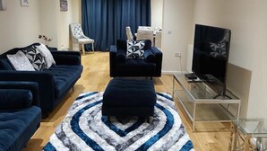 Uma sala de estar com sofá, pufê e mesa de centro de vidro.