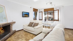 Una sala de estar con chimenea, un sofá, una mesa de comedor y un televisor.