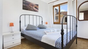 Un dormitorio con cama, mesita de noche, lámpara y un cuadro en la pared.