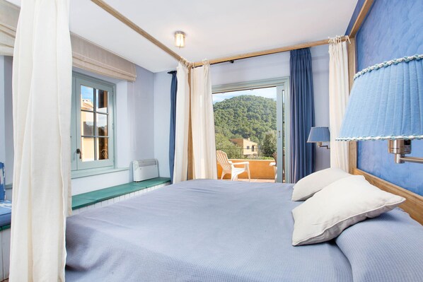 A bedroom with a large bed, a view of the outdoors, and a window with curtains.