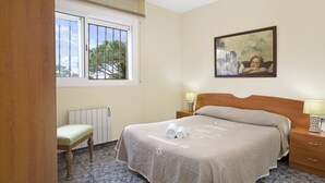 Une chambre d’hôtel avec un lit, une table de chevet, une chaise et une fenêtre avec des stores.