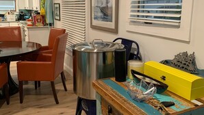 A dining area with a wooden table and chairs, a kitchen in the background, and a window with blinds. - Lagoon access and views . Close Restaurants and  minutes from LBI (Manahawkin)