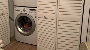 A laundry room with two stacked front-loading washing machines and a closed white closet with horizontal slats. - Lagoon access and views . Close Restaurants and  minutes from LBI (Manahawkin)