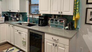 A kitchen with white cabinets, a dishwasher, a coffee maker, and a window with a view. - Lagoon access and views . Close Restaurants and  minutes from LBI (Manahawkin)