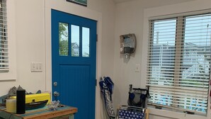 A room with a blue door, a window with blinds, a table with various items, and a chair. - Lagoon access and views . Close Restaurants and  minutes from LBI (Manahawkin)