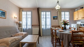 Un accogliente soggiorno con un divano, un tavolo in legno e un'area pranzo con sedie e tavolo apparecchiato per due persone.