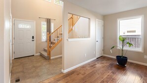 Un hall d’entrée spacieux avec un plancher en bois, un escalier et une plante en pot.