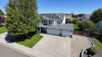 A two-story house with a garage, a covered porch, and a well-maintained lawn.