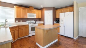 Une cuisine avec des meubles de rangement en bois, un réfrigérateur blanc, un four à micro-ondes et une cuisinière.