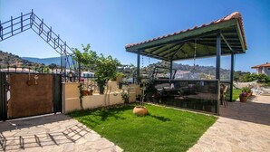 A private patio with a covered seating area, a stone pathway, and a view of the surrounding landscape. - Inviting 4-Bed Villa Nil Dalyan with child pool (Ortaca)