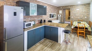 Une cuisine moderne équipée d’un réfrigérateur en acier inoxydable, d’un four à micro-ondes et d’un coin repas avec une table et des chaises.