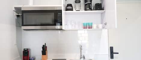 Une cuisine moderne équipée d’un four à micro-ondes, d’une machine à café et d’un évier.
