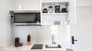 A modern kitchen with a microwave, coffee maker, and a sink.