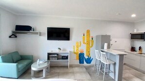 A modern living room with a green sofa, a small coffee table, and a TV mounted on the wall.