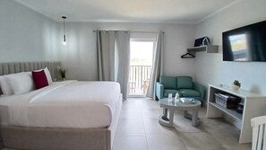 A hotel room with a bed, a seating area, a TV, and a balcony.